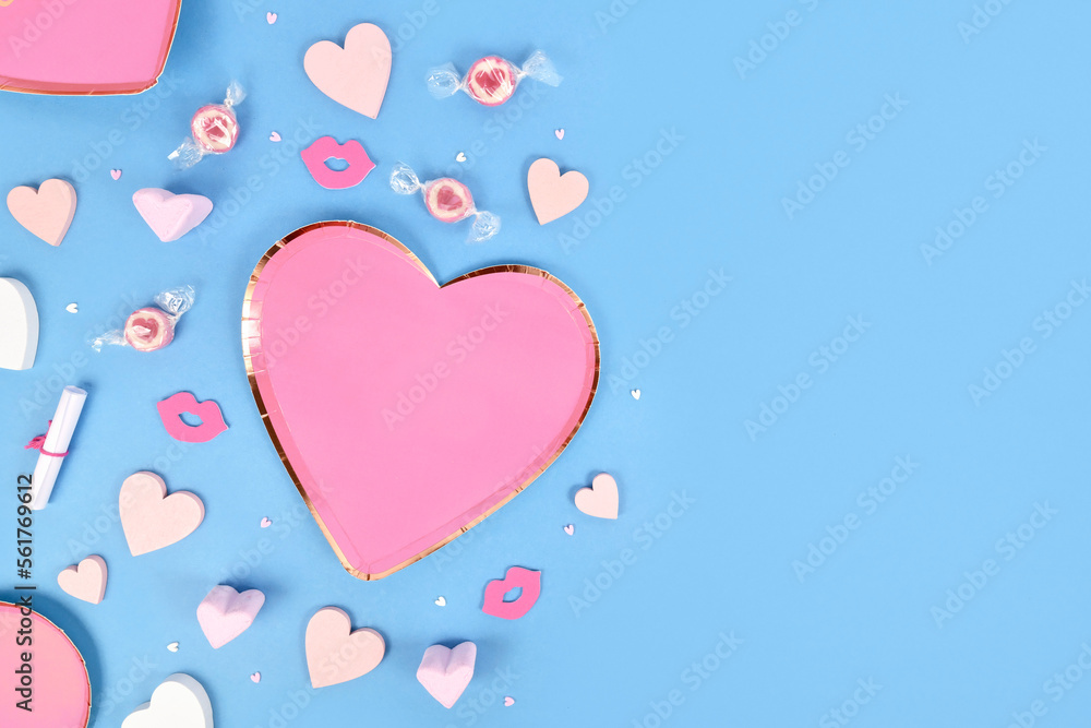 Valentine's Day flat lay with heart shaped plates, heart ornaments and candy on blue background with copy space