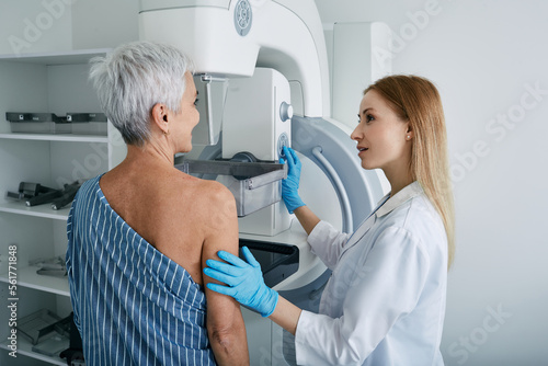 Senior woman having mammography scan at hospital with medical technician. Mammography procedure, breast cancer prevention photo