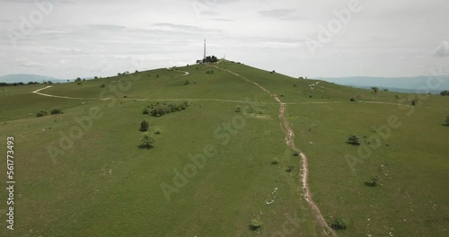 Drone shot of the top of mountain Slavnik with green meadows and off road paths to the top where is radio tower. Cloudy weather. photo