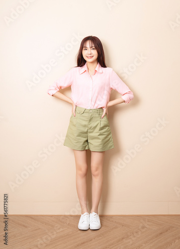 Full length photo of young Asian woman standing on background
