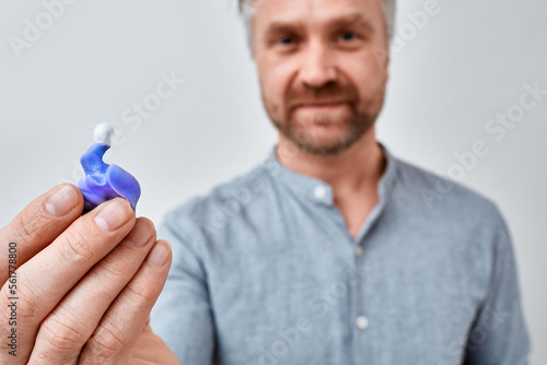 Individual custom earplugs for adults. Man holding customized earplug for protecting hearing in front of him photo