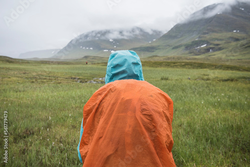 Hiker standing in rain in lush TjÃ¤ktjavagge near SÃ¤lka hut, Kungsleden trail, Lapland, Sweden photo