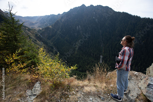 casual guy with tied hair and dark glasses looking at the mountains on a sunny day. view from behind. sunny mountains panorama