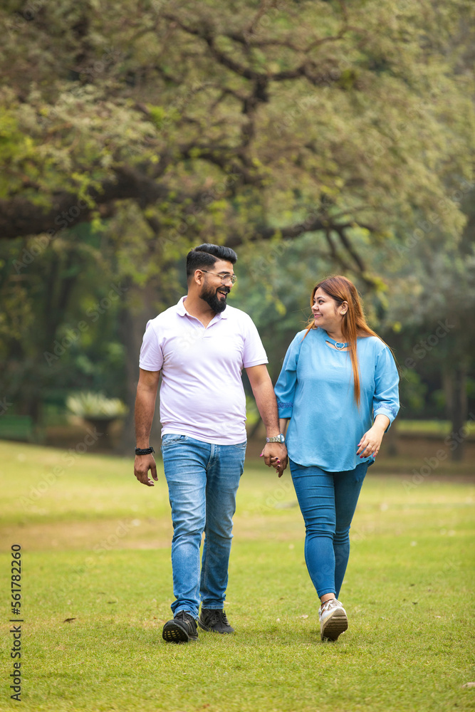 Fototapeta premium young indian couple holding hand each other and walking in park.