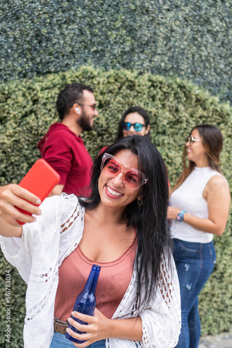 Latin woman taking a selfie near friends