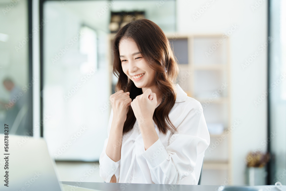 Portrait of a woman business owner showing a happy smiling face as he has successfully invested her business using computers and financial budget documents at work Portrait of a woman business owner showing a happy smiling face as he has successfully invested her business using computers and financial budget documents at work