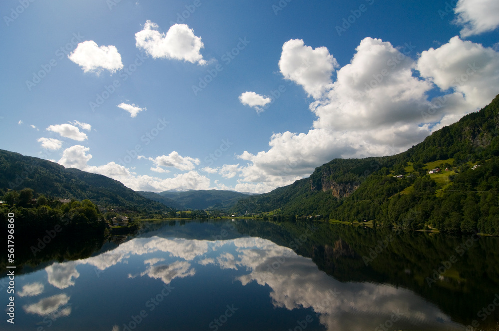 Obraz premium Mountains, clouds and sky reflected in the lake at Norheimsund on the Hardanger fjord, Western Norway.