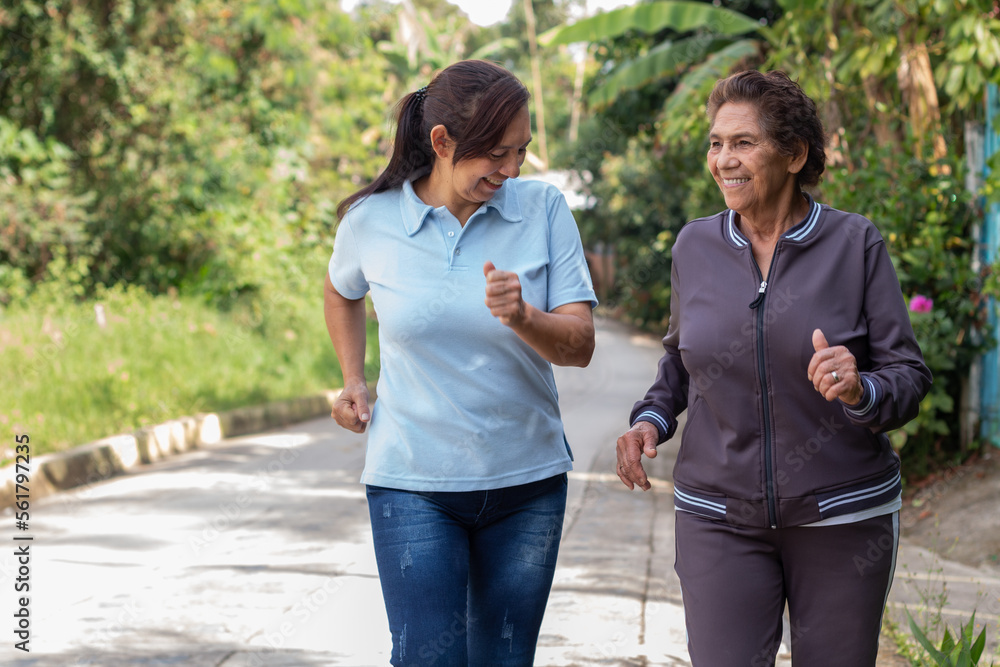 Cheerful elderly mother and daughter jogging outdoors in a morning exercise. Healthy living concept