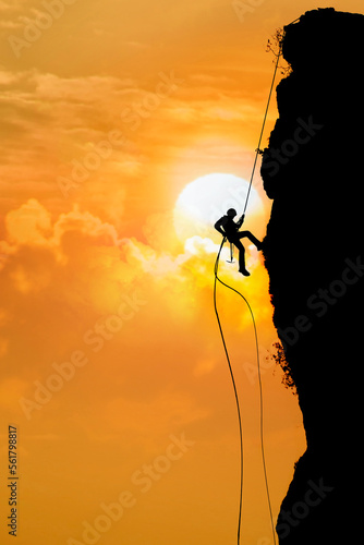 Mountaineer climbing at sunset on dramatic cloudy background.