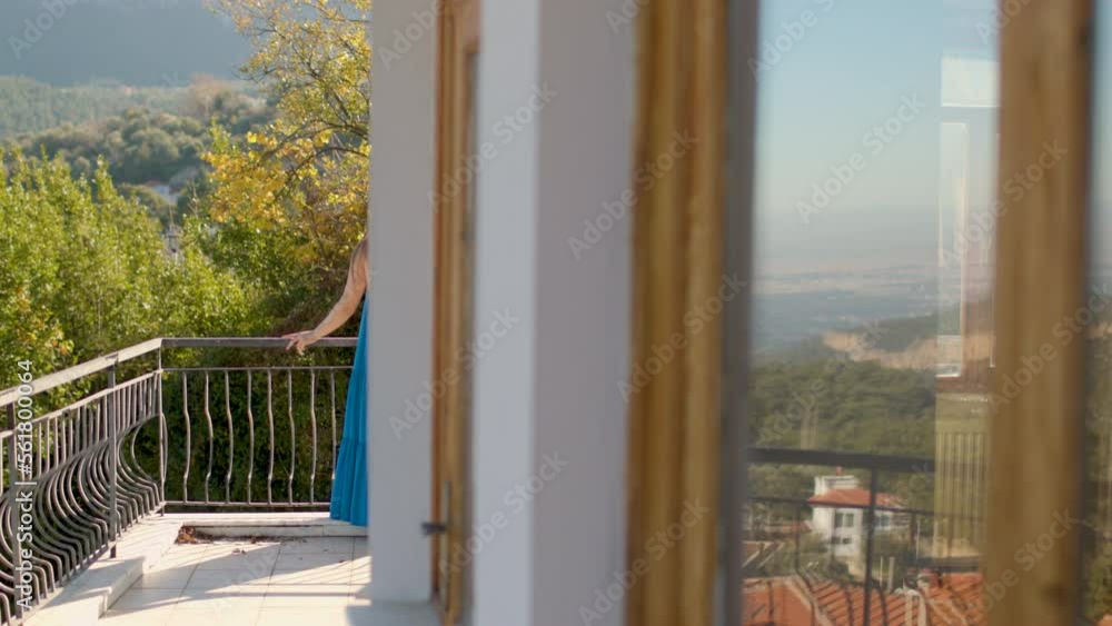 a girl in a beautiful blue dress stands on the balcony of a country house a girl in a beautiful blue dress stands on the balcony of a country house