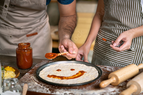 happy smile love couple made pizza with sauce fun face on pizza before cook stove or oven in family relax activity in kitchen room with food and drink for healthy dinner