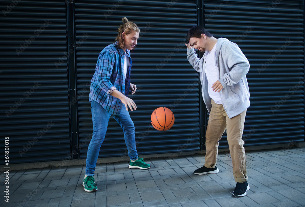 Man with down syndrome playing basketball outdoor with his friend. Concept of friendship and integration people with disability into society. Man with down syndrome playing basketball outdoor with his friend. Concept of friendship and integration people with disability into society.
