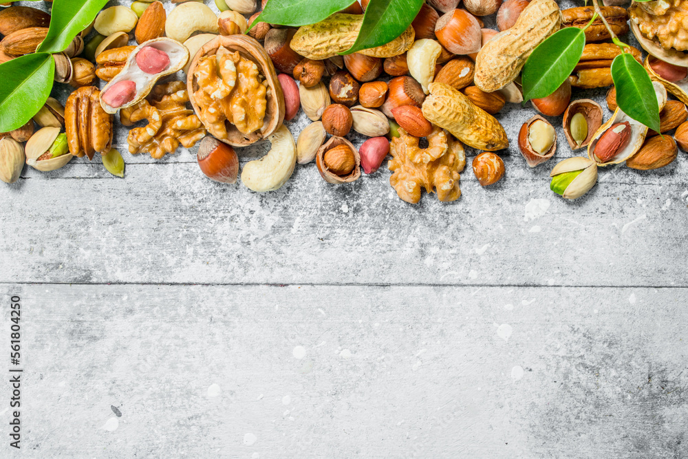 Nuts background.Assortment of different types of nuts with green leaves.