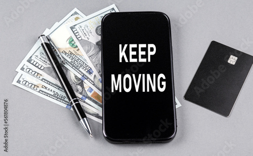 Credit card and text KEEP MOVING on smartphone with dollars and pen. Business