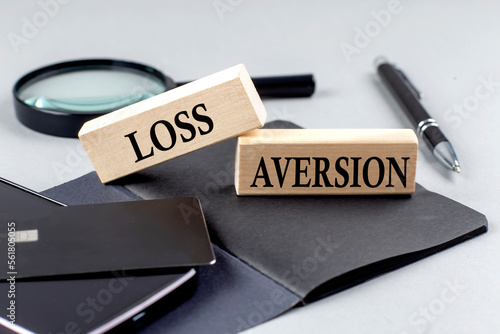 LOSS AVERSION text on wooden block on black notebook , business concept