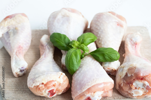 Raw chicken legs. On a white background. Salt, pepper, leaves