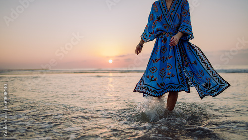 Low section of woman in orient dress enjoying sea. photo