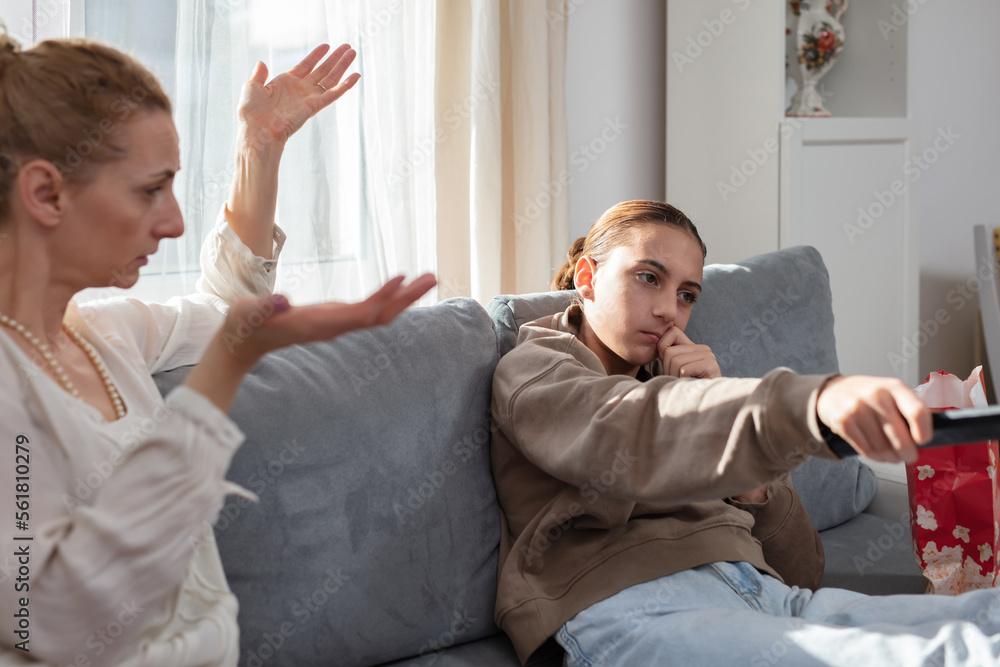 Obraz premium Mother having trouble with a lazy teenager girl at home while watching TV.