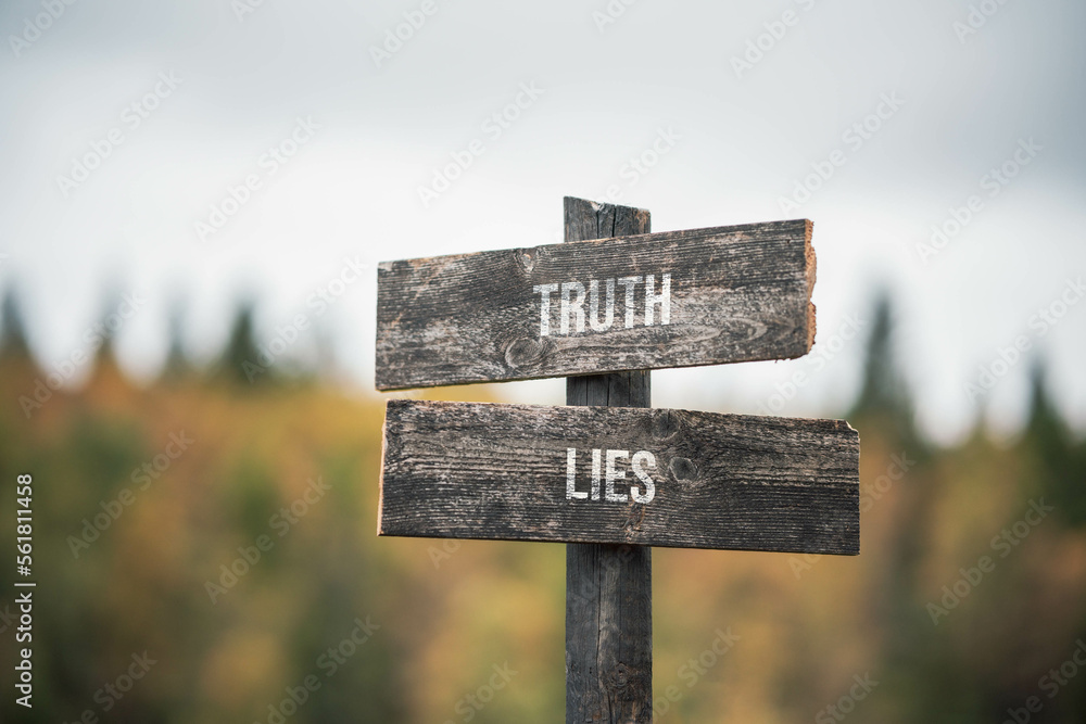 vintage and rustic wooden signpost with the weathered text quote truth lies, outdoors in nature. blurred out forest fall colors in the background.