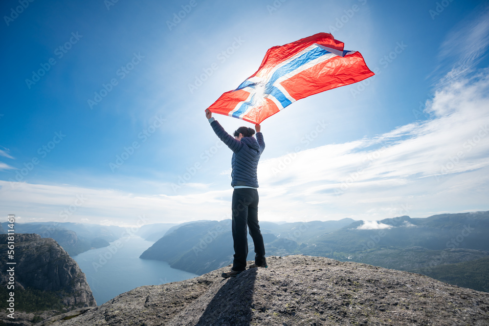 Obraz premium Woman with a waving flag of Norway on the background of nature