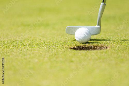 Close-up Golf ball in the sand, putter on a background.