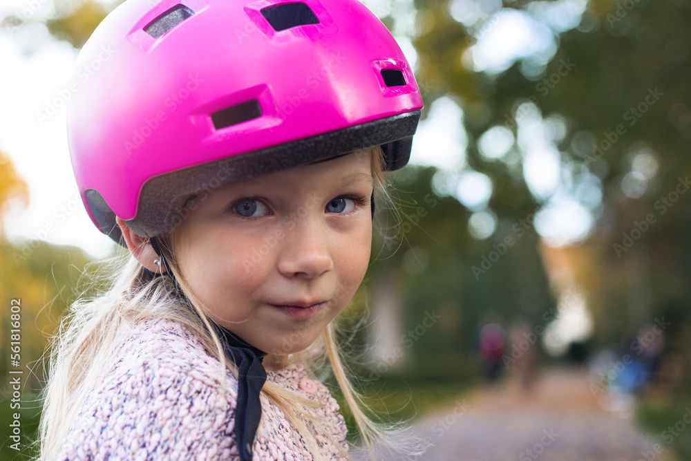Sad child girl in a pink helmet in the park Sad child girl in a pink helmet in the park