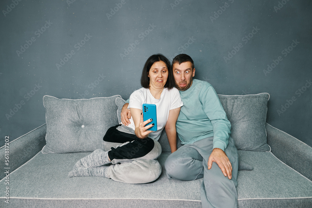 Millennial couple with disgust expression looking at smartphone Millennial couple with disgust expression looking at smartphone