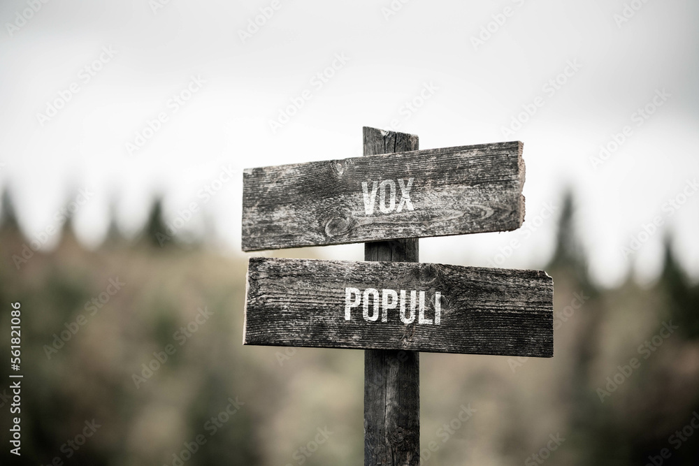 vintage and rustic wooden signpost with the weathered text quote vox populi, outdoors in nature. blurred out forest fall colors in the background.