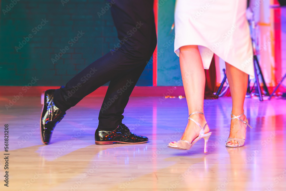 Dancing shoes of a couple, couples dancing traditional latin argentinian dance milonga in the ballroom, tango salsa bachata kizomba lesson, festival on wooden floor, red, purple and violet lights