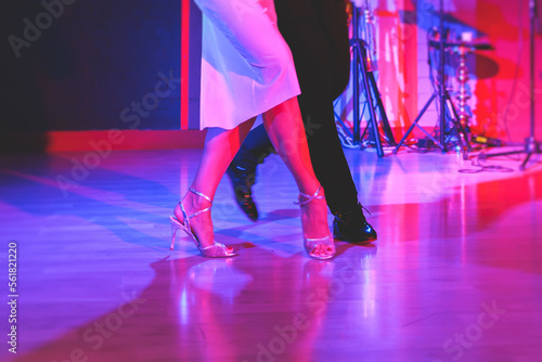 Dancing shoes of a couple, couples dancing traditional latin argentinian dance milonga in the ballroom, tango salsa bachata kizomba lesson, festival on wooden floor, red, purple and violet lights