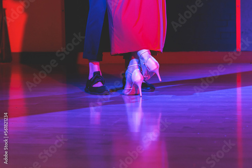 Dancing shoes of a couple, couples dancing traditional latin argentinian dance milonga in the ballroom, tango salsa bachata kizomba lesson, festival on wooden floor, red, purple and violet lights