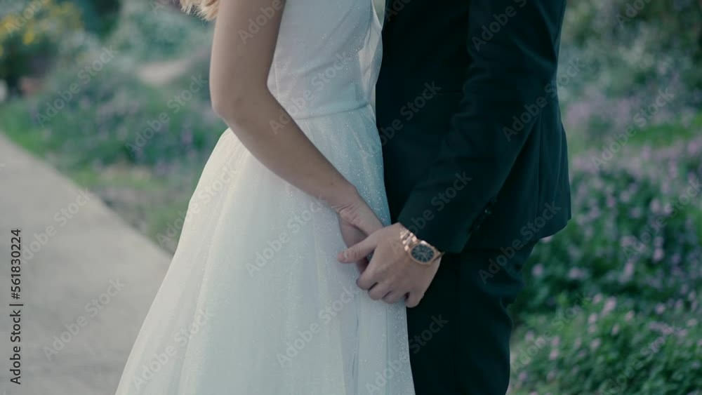A bride and groom are standing in a beautiful park on the path, facing each other and holding hands. A bride and groom are standing in a beautiful park on the path, facing each other and holding hands.