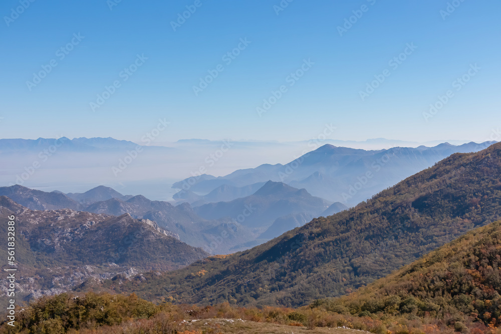 Panoramic view of dramatic karst mountain chains Dinaric Alps surrounding the Lake Skadar National Park seen from Goli Vrh, Montenegro, Balkan, Europe. Valley is covered by mystical fog, blue hills Panoramic view of dramatic karst mountain chains Dinaric Alps surrounding the Lake Skadar National Park seen from Goli Vrh, Montenegro, Balkan, Europe. Valley is covered by mystical fog, blue hills