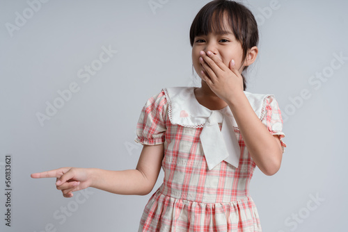 Child with gesture smells bad. Child covers nose with hand, smells something awful, pinches nose, frowns in displeasure and pointing finger to camera. Teenager showing that something stinks. photo
