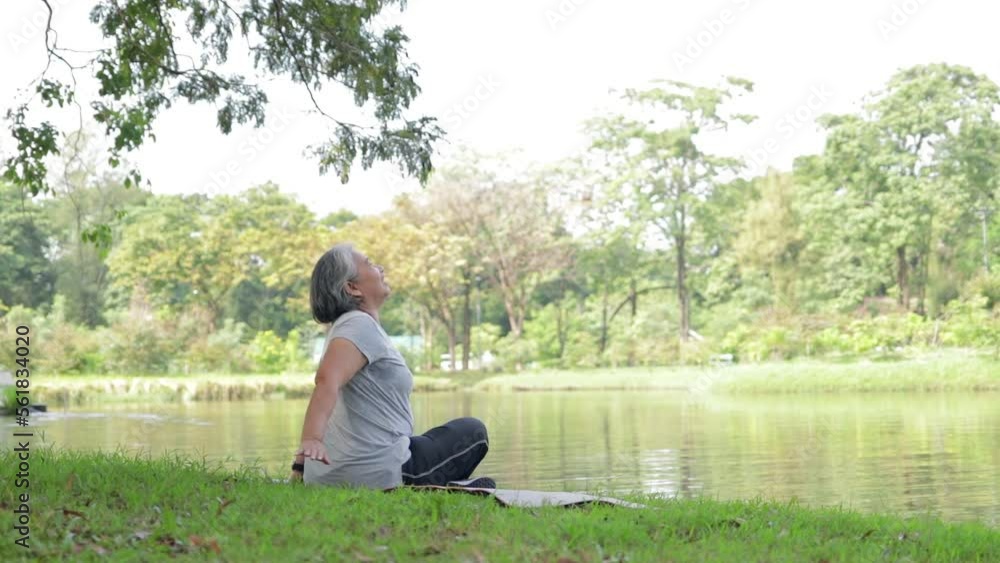 Asian senior woman sitting exercising by the pool in the park in the morning. Happy. Healthy body. Sports concept, health care of the elderly to stay healthy. copy space Asian senior woman sitting exercising by the pool in the park in the morning. Happy. Healthy body. Sports concept, health care of the elderly to stay healthy. copy space