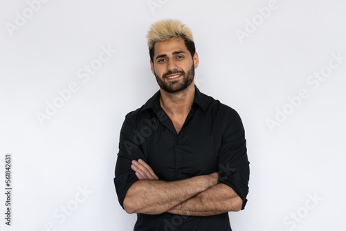 Winsome businessman with crossed arms. Male Caucasian model with brown eyes, ombre painted hair and beard in black shirt smiling keeping his hands crossed. Lifestyle concept © Mangostar