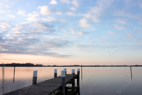 Tranquil fjord view with wooden jetty at dawn.