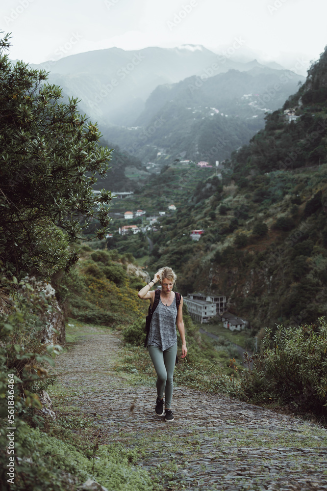Naklejka premium Adventurous girl is hiking a path up the hill