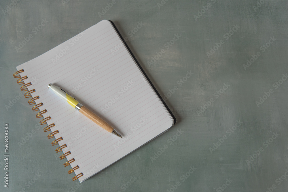 Cahier ouvert sur une page blanche avec un stylo Photos | Adobe Stock