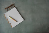 Cahier ouvert sur une page blanche avec stylo et lunettes