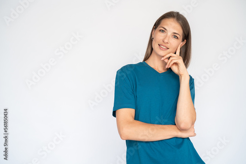 Satisfied Caucasian woman leaning on hand. Portrait of pleased young female model with brown hair in blue T-shirt looking at camera  smiling  thinking about ads. Advertising concept