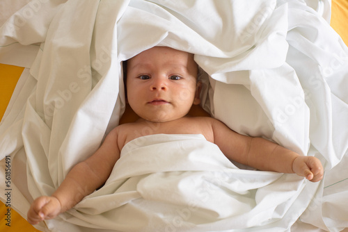 Newborn baby lifting his head under the blanket