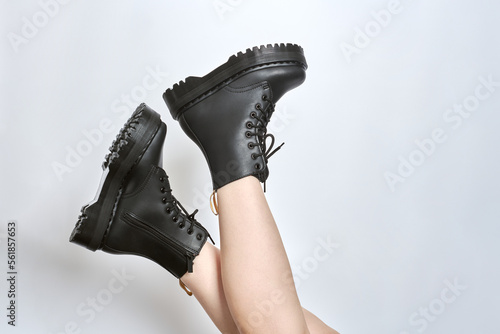 Fotografia Woman legs in black combat boots on high heel platform with lug soles upside down side view on isolated white background