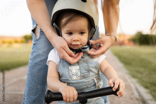 woman mother put on protective helmet on head of her daughter child