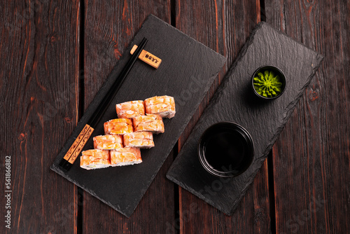 Japanese kitchen - sushi roll with cucumber and cream cheese topped with shrimp on black board top view