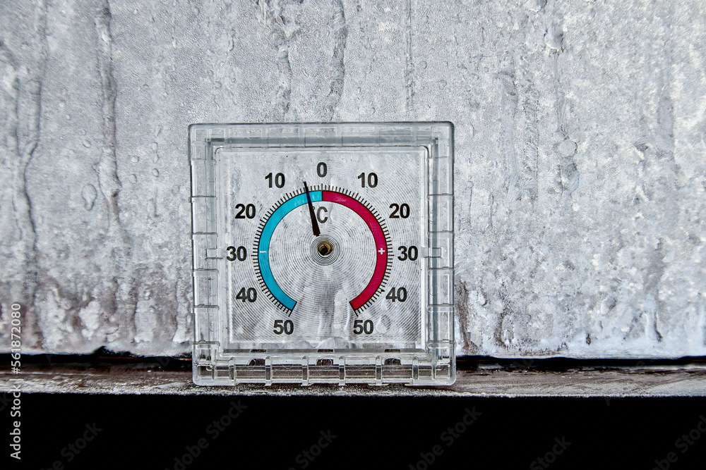 Naklejka premium Thermometer with minus frost on the glass, freezing, cooling, temperature decrease patterns on the window.