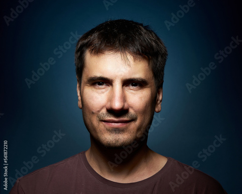 Portrait of a 42-year-old brunette man on a dark background with bright illumination