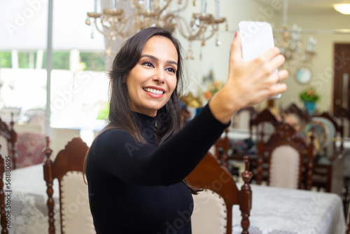 Uma jovem feliz vestindo uma blusa preta de manga comprida, tirando uma selfie.