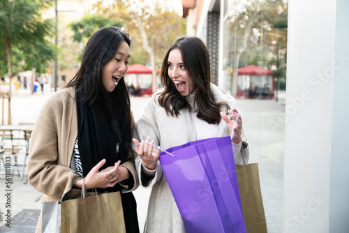 Two beautiful women looking inside shopping bags in the ctiy - sale, shopping, tourism and happy people concept 