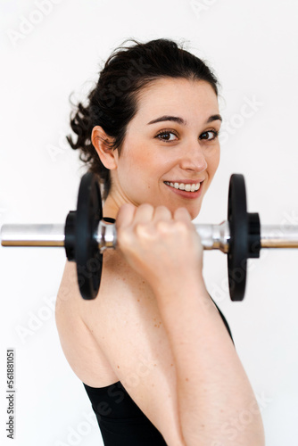 Portrait of a young beautiful woman lifting a dumbbell